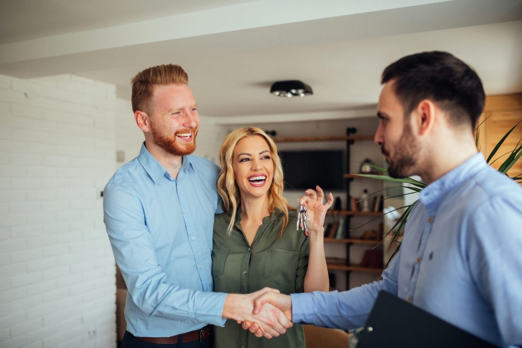  renting apartment from agent, man and woman with keys shaking hand with agent