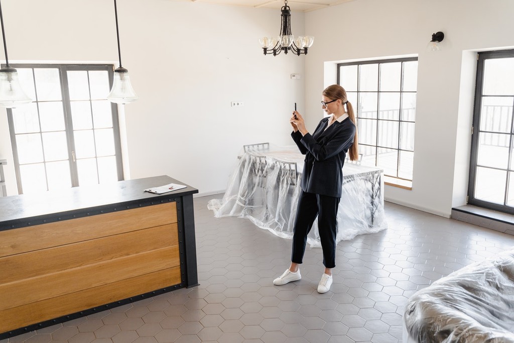 woman taking pictures of a room filled with packed furniture