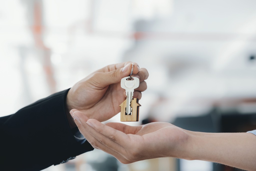 one hand giving a pair of keys to another hand 