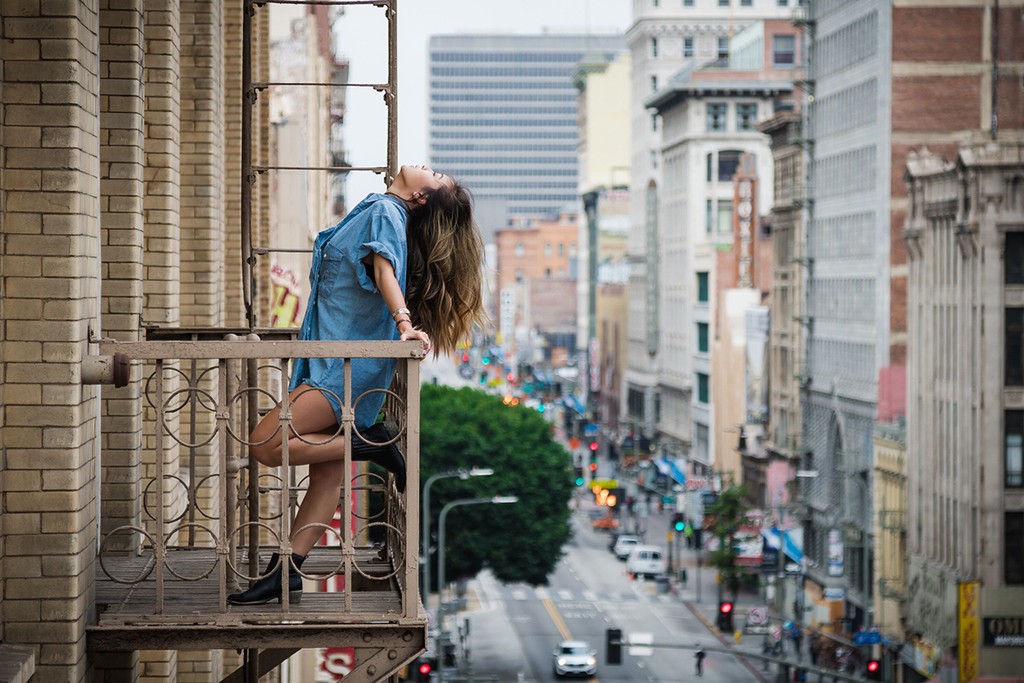 women leaning over balcony with a busy road in the background