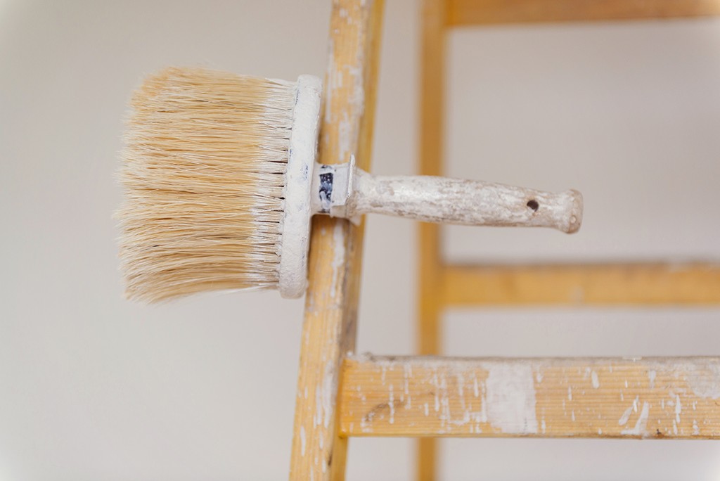 Preparing to paint the wall. Detail of paintbrush on ladder.