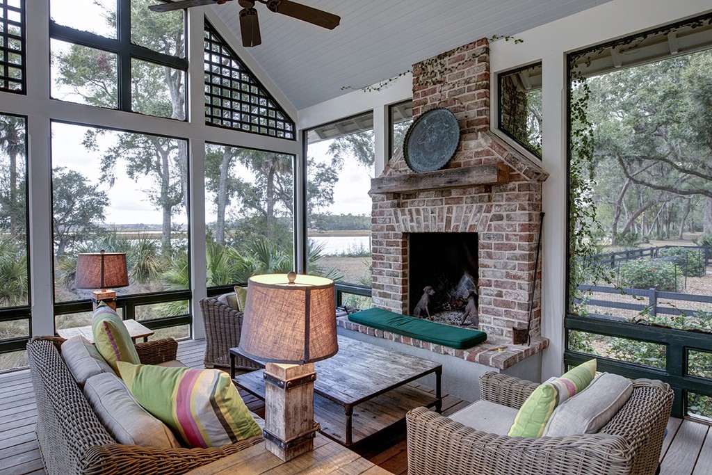 Luxurious three season screen porch with fireplace, looking out onto waterfront property.