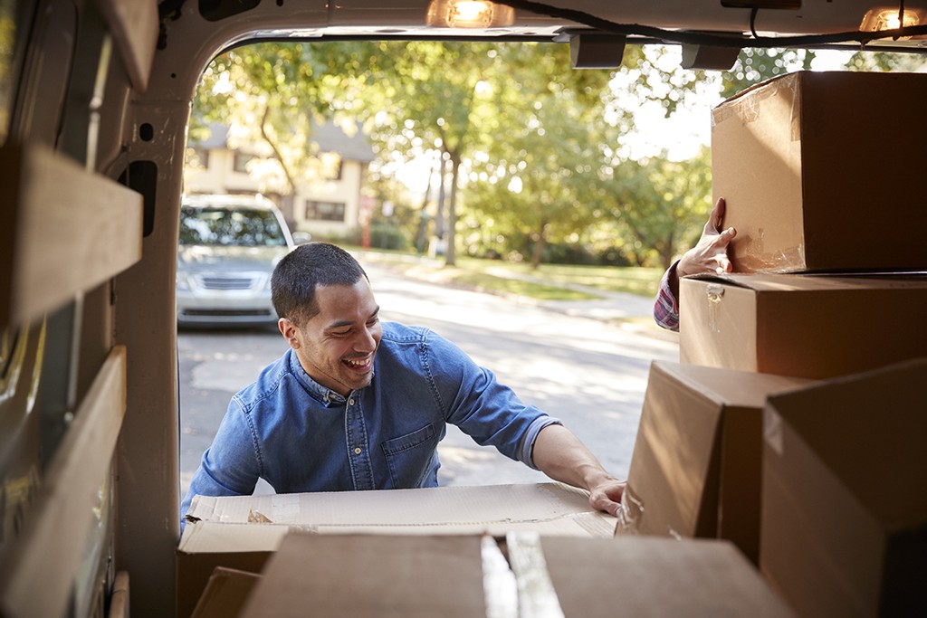 Couple Unloading Boxes From Van On Family Moving In Day