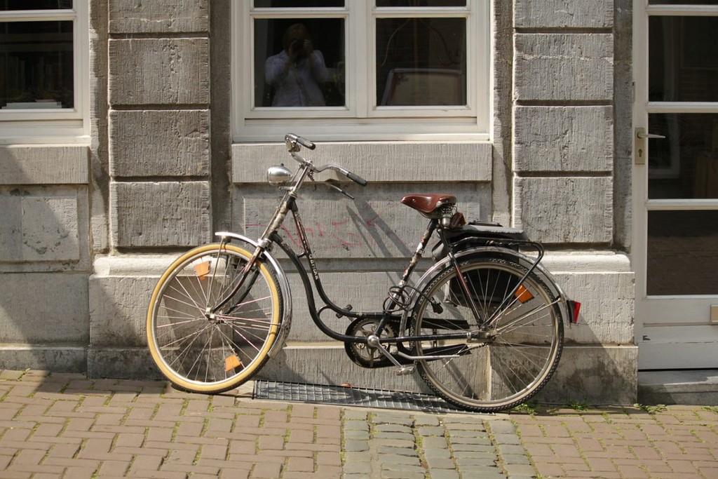 A bicycle leaning against a wall outside.