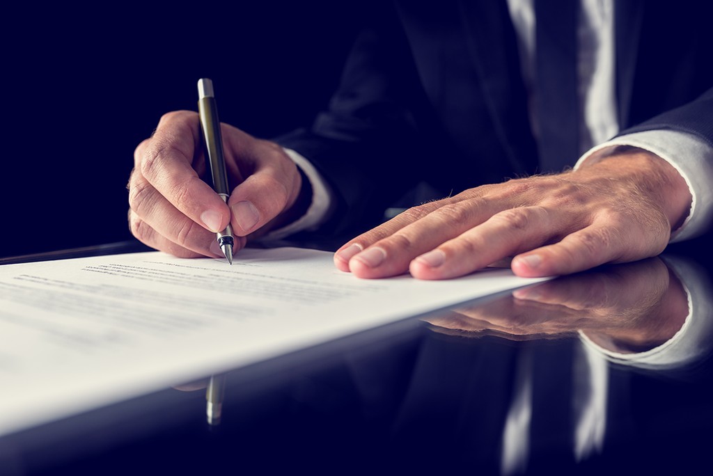 Retro image of lawyer signing important deed of trust on black desk. Over black background.