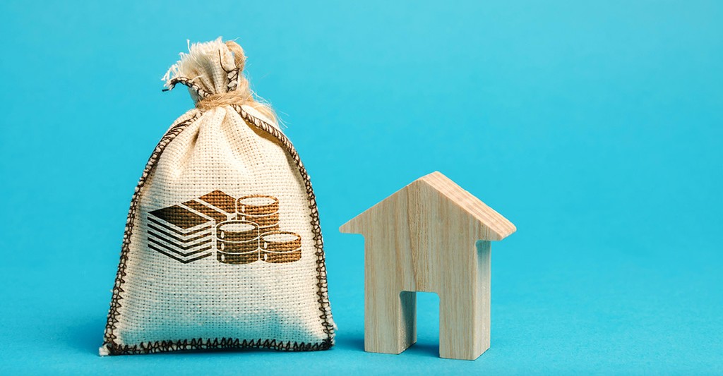 Money bag and wooden house. Concept of real estate market budget. Investment in construction. Saving money to buy a home or apartment. Affordable housing. Mortgage and loan. Landlord tax. Debt repayment