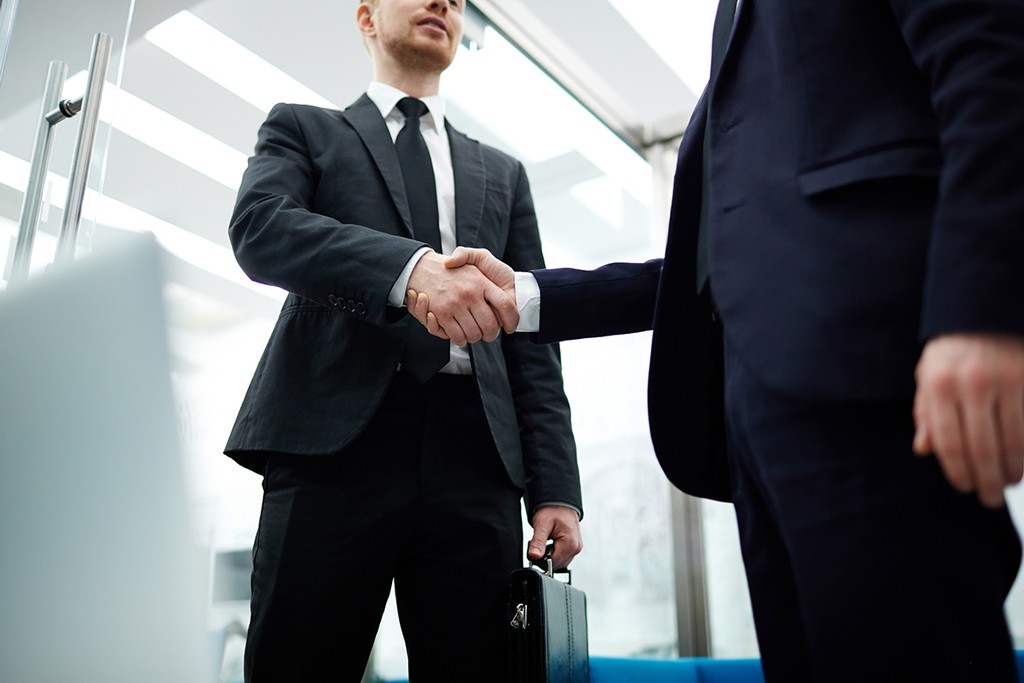 Businessmen in suits handshaking to signify deed of trust