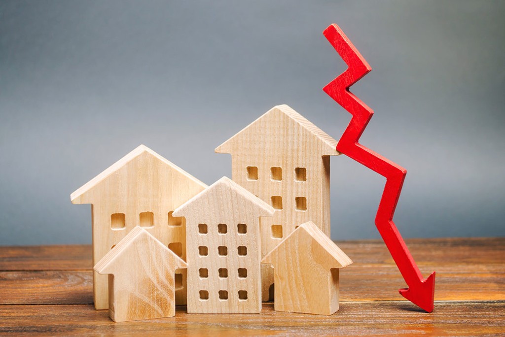 wooden house models with a red downward arrow signifying Property business losses