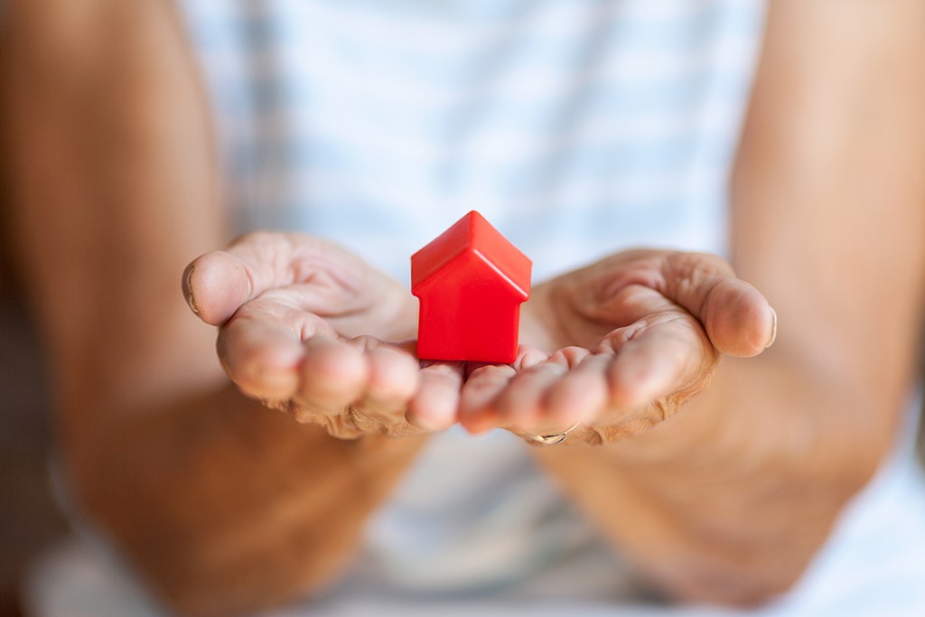 Elderly woman holding a small house in her hands