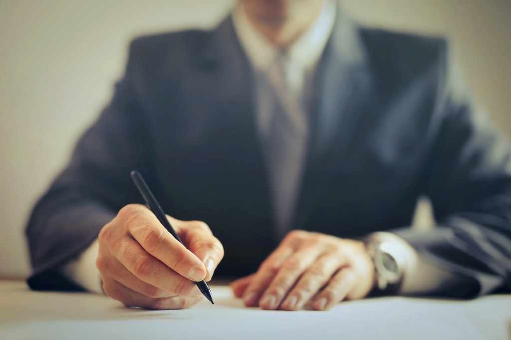 contract being signed by man in suit holding a pen 