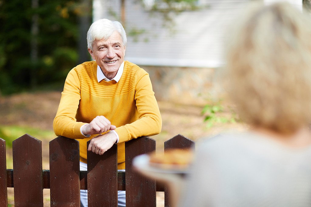 two neighbours talking between a fence