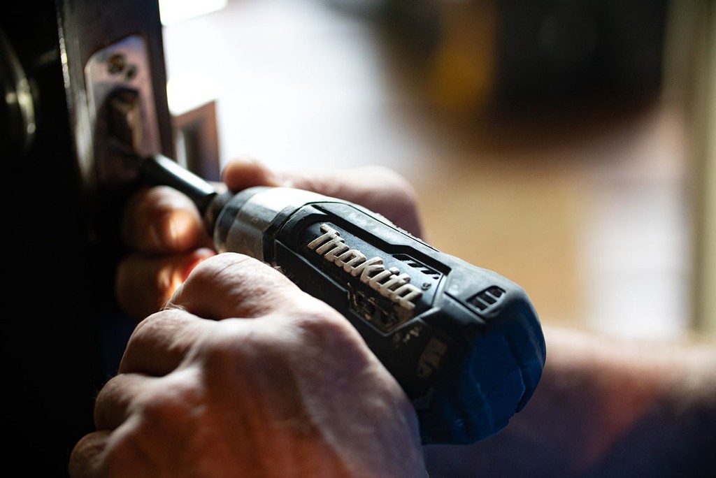 someone undertaking repairs on a lock with a Makita drill