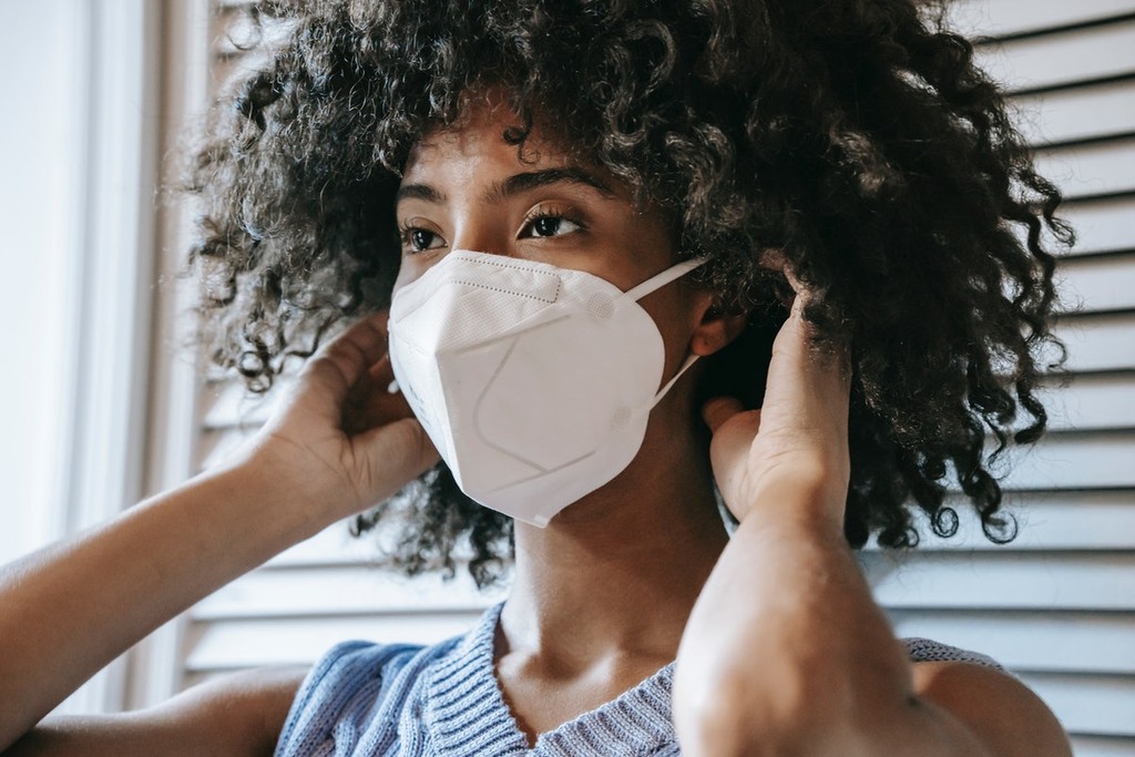 A woman putting on a protective mask, essential for house viewings during covid.