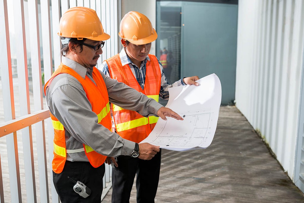 Negotiating with a contractor at a building in fluorescent suits 