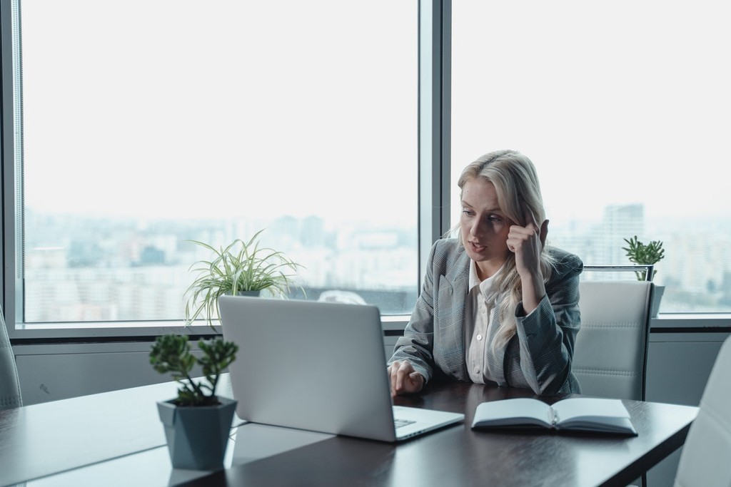 woman in grey suit using laptop and speaking to a proptech agent