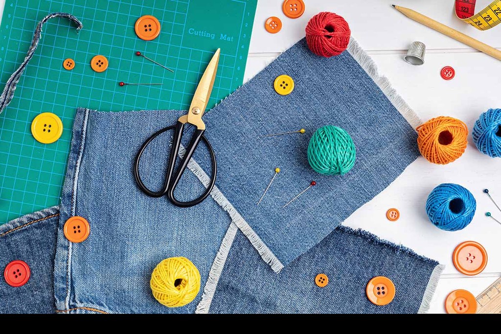 Upcycling old jeans on a craft table with colourful fabrics and scissors  