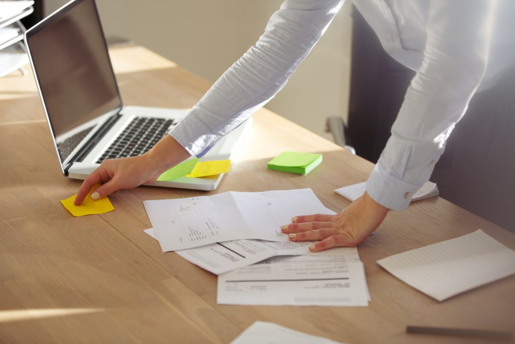 woman placing post it notes on the table next to laptop