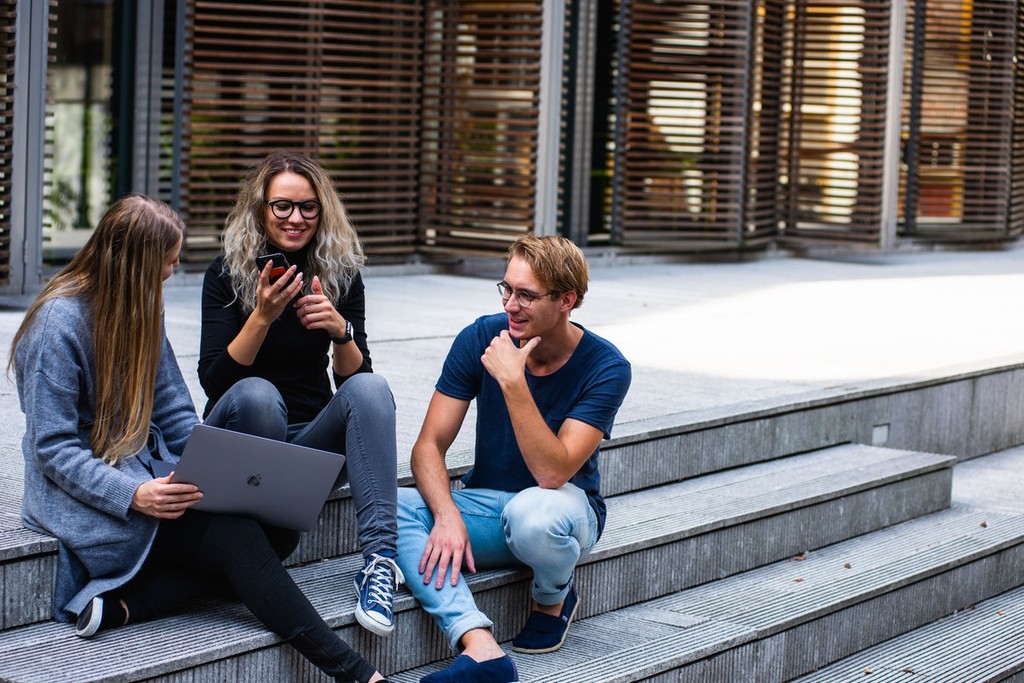 three people sitting on concrete steps