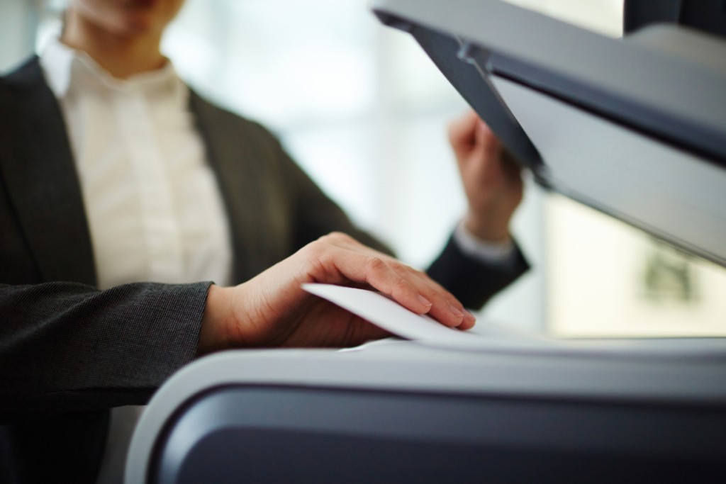 Secretary making copies or scanning papers on photocopier