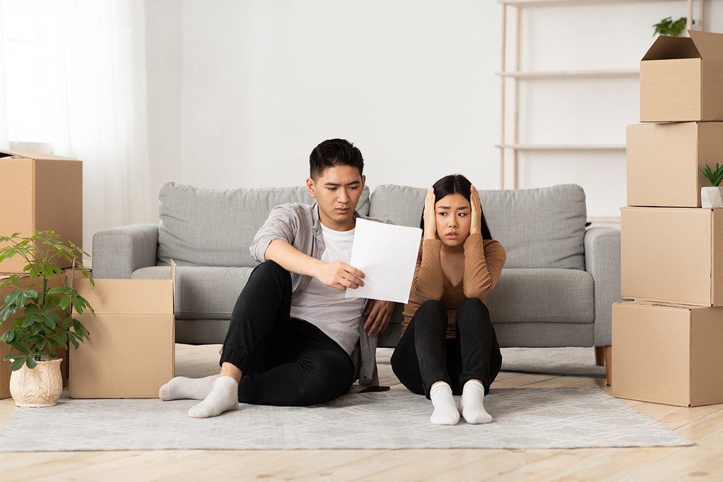 eviction notice given to two stressed out tenants by a grey sofa