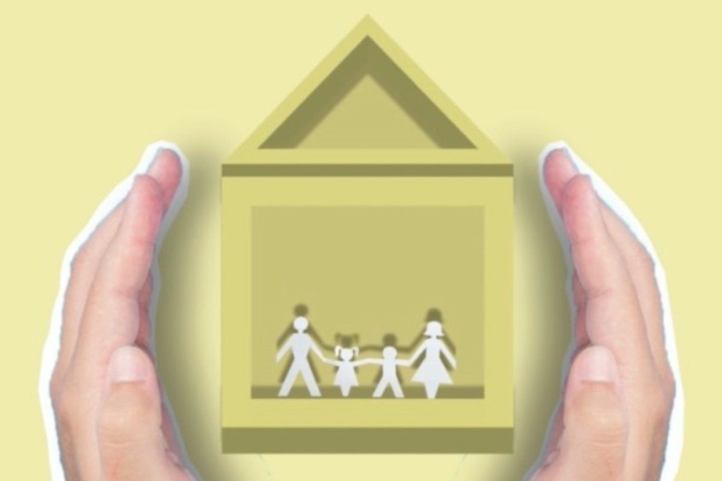 family paper cutout in a yellow house inside human palm