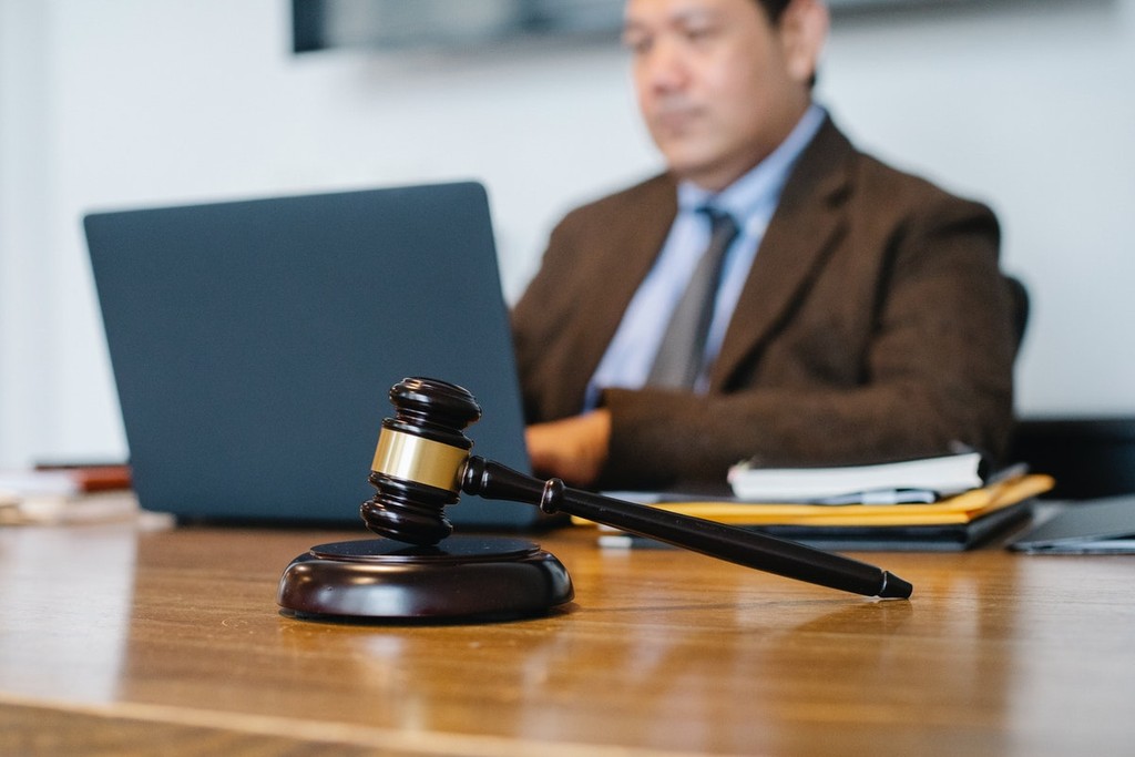 man using latop with a gavel placed next to him