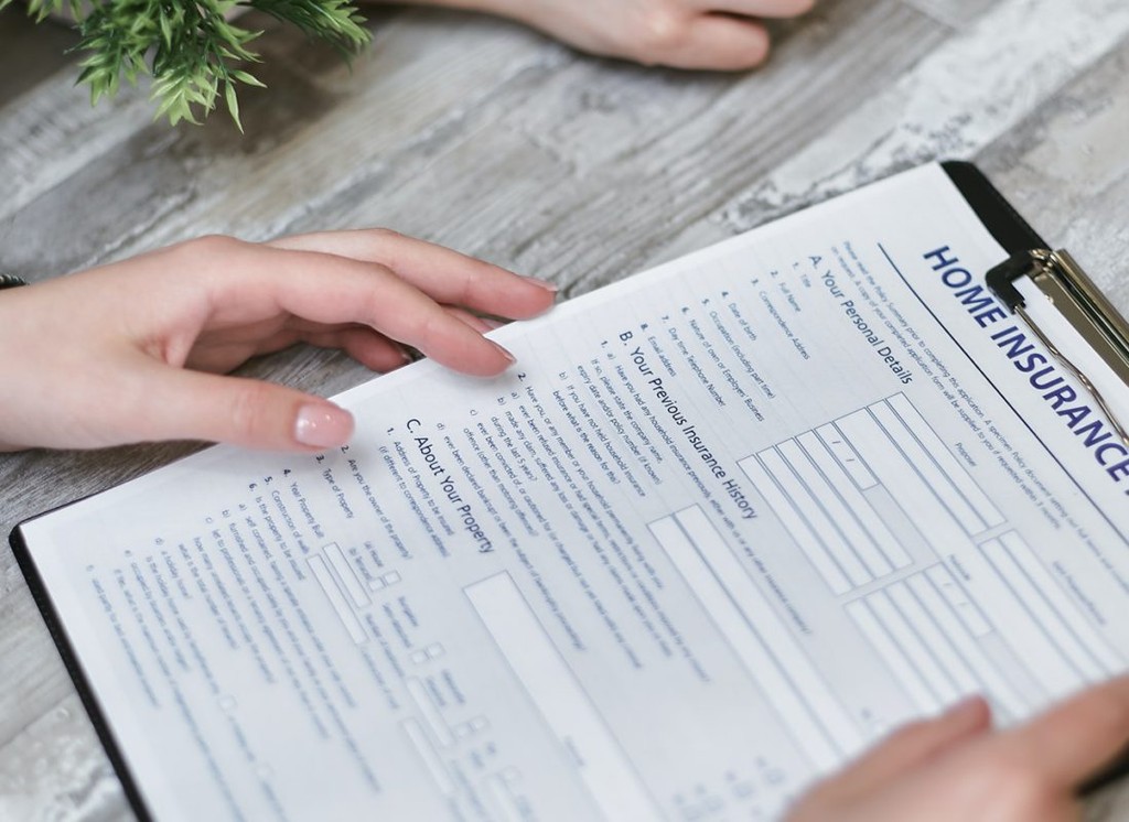 A person's hands holding a home insurance document.