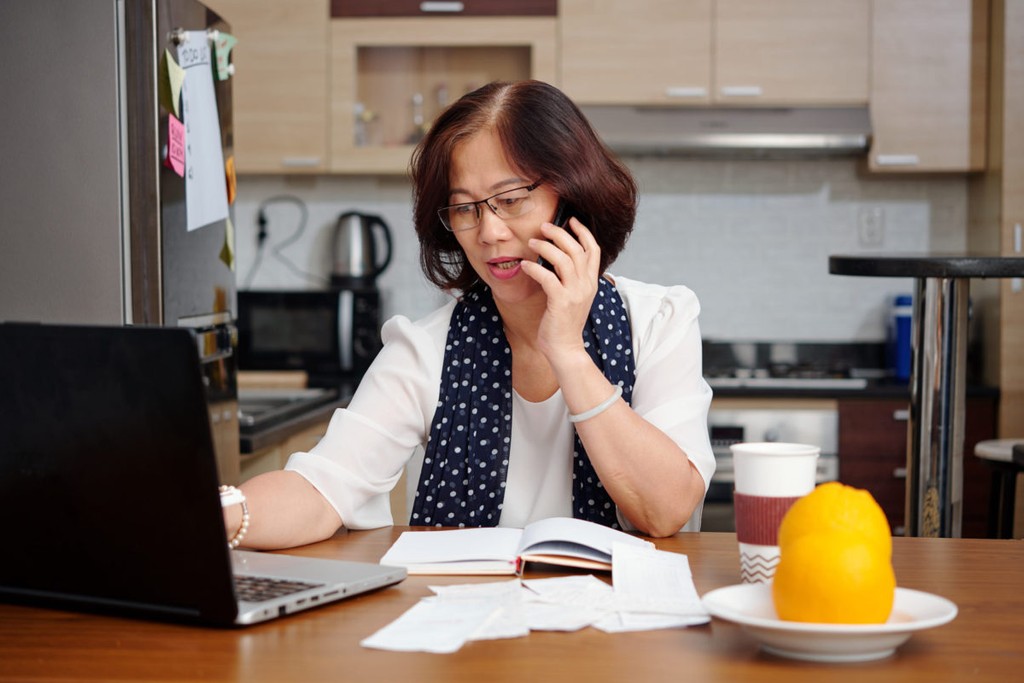 woman on the phone with laptop in sight next to some oranges