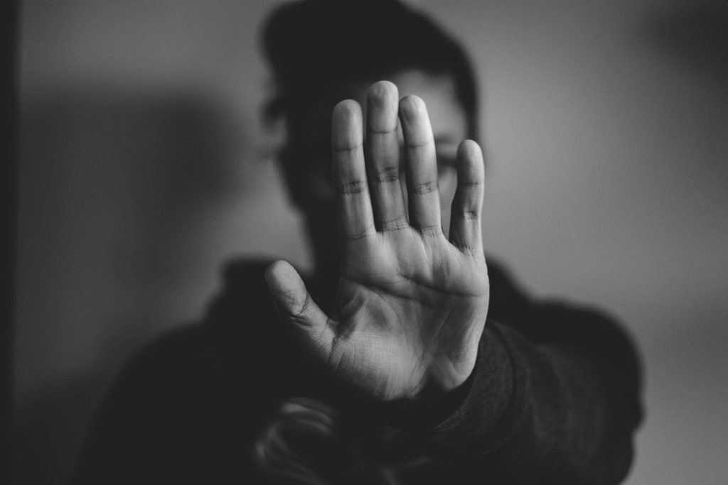 black and white image of someone raising there hand up to say stop there