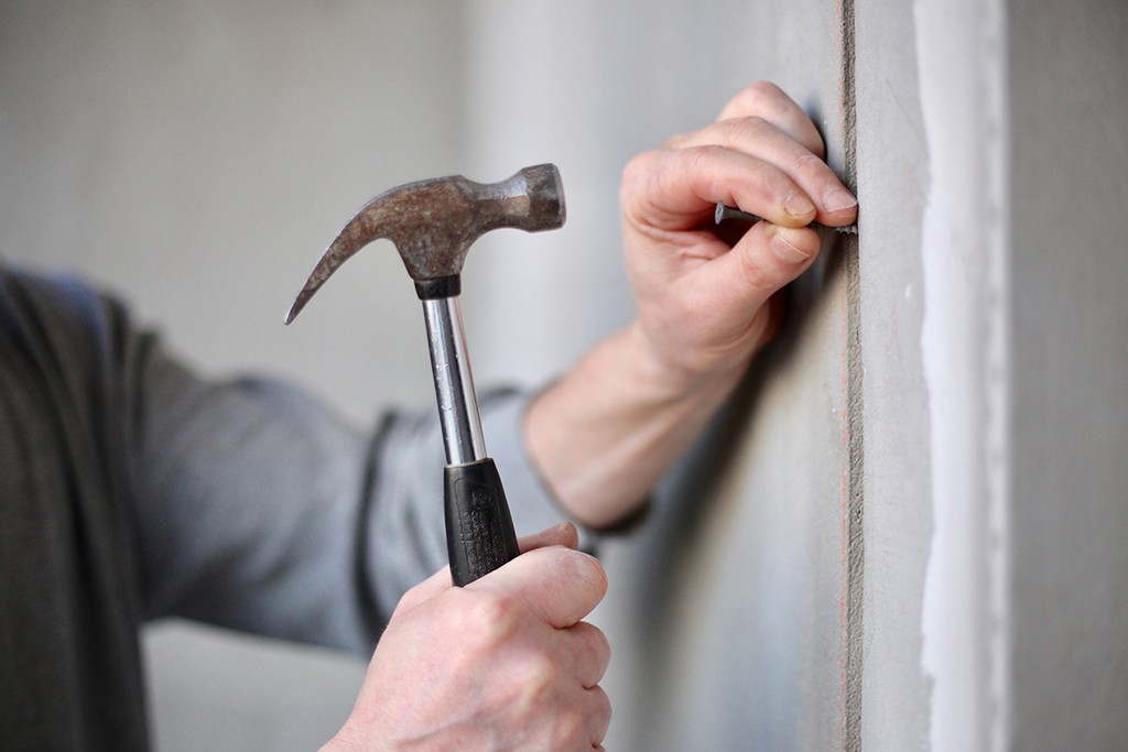 Property maintenance making repairs using a hammer and nail