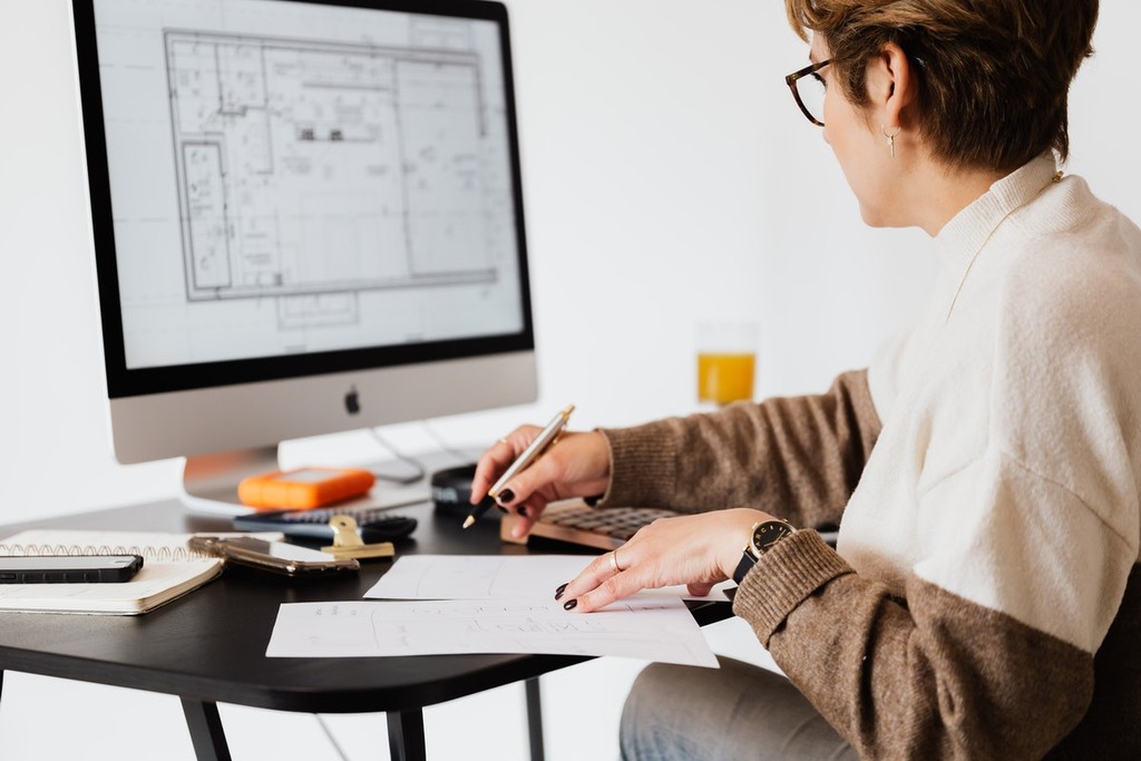 woman using a computer screen and writing on paper