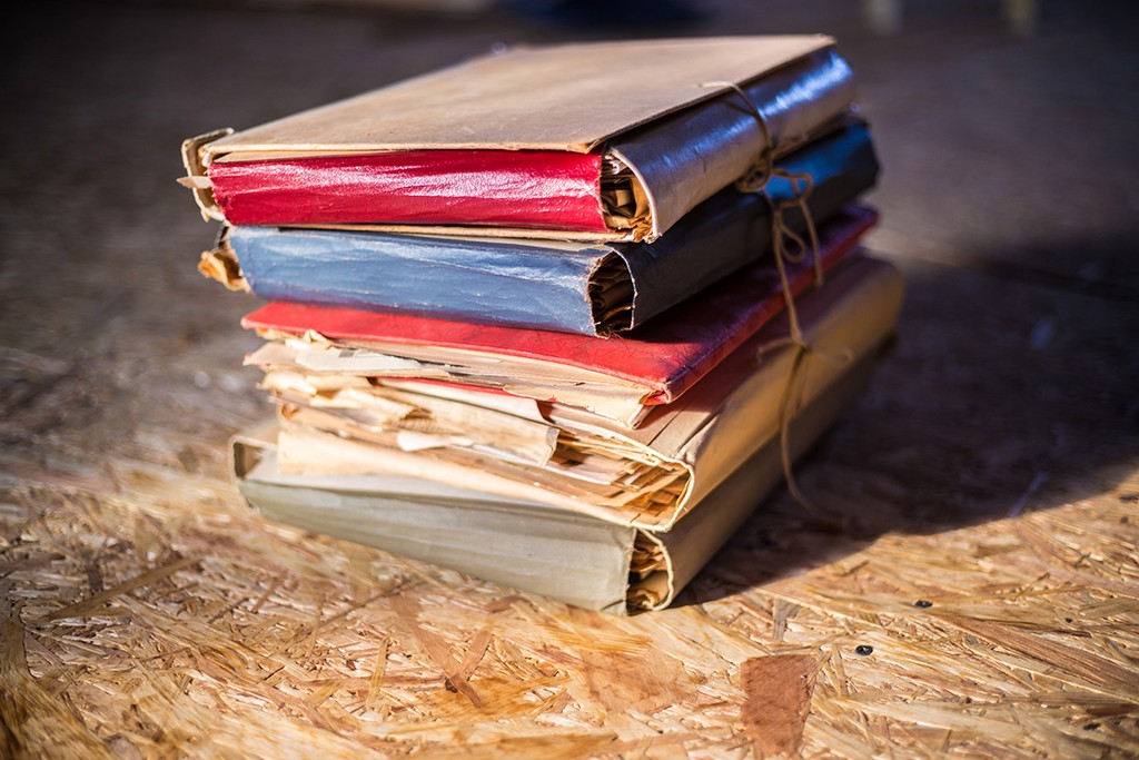 Pile of old documents in colorful cardboard folders signifying records kept by landlords for rent arrears