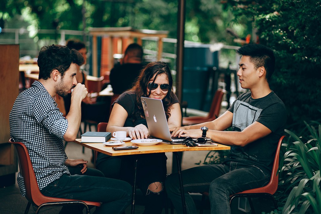 three students socialising in London with a laptop open on the table